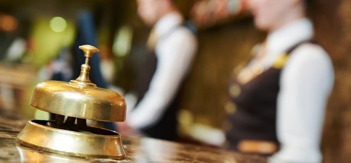 A bell at a hotel reception and two receptionists, hospitality