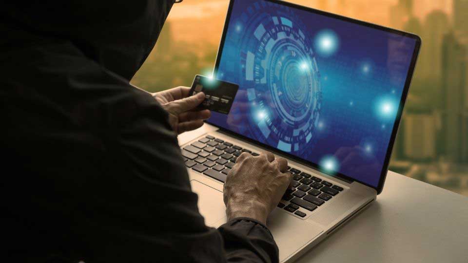 Person holding a card in front of a laptop